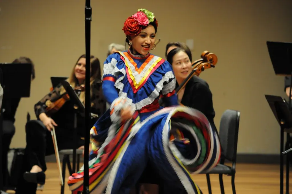 Bailarina de folclórico con vestido azul frente a la orquesta